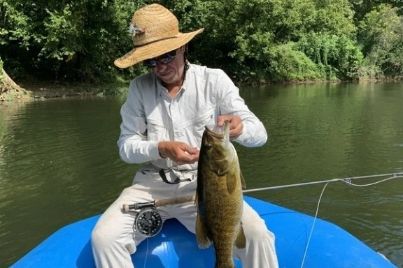 a man holding a fish on a boat in a body of water